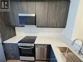 Clarington (Bowmanville) condo for rent - A modern kitchen with dark wood cabinets and stainless steel appliances.