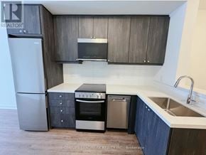 Clarington (Bowmanville) condo for rent - A modern kitchen with a refrigerator, oven, dishwasher, and microwave.