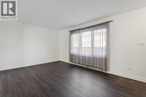 Sarnia townhouse for rent - A room with wooden floors and a window with curtains.