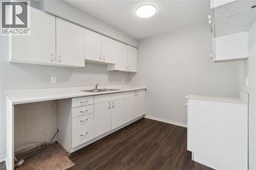 Sarnia townhouse for rent - A kitchen with white cabinets and a brown floor.