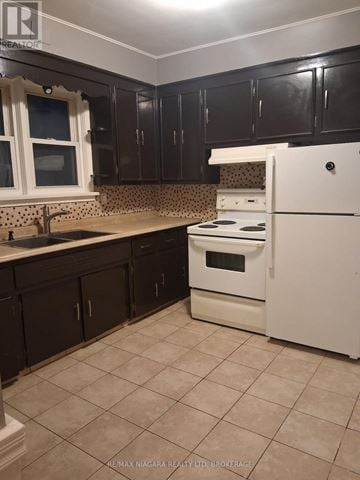 Niagara Falls (Downtown) apartment for rent - A kitchen with black cabinets and a white fridge.