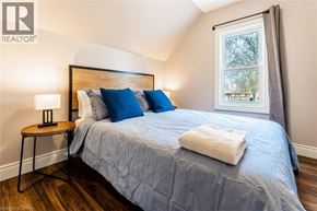 Stratford apartment for rent - A bedroom with a bed, a table with a lamp, and a window.