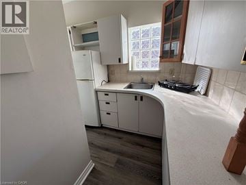 Hamilton apartment for rent - A kitchen with white cabinets and a window with a purple and white curtain.