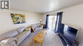 Grande Prairie apartment for rent - A living room with a grey sofa, a wooden coffee table, and a flat screen TV.