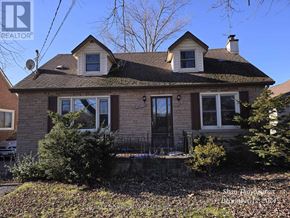 Niagara Falls (West Wood) apartment for rent - A house with a brown roof and a black door is surrounded by bushes and trees.