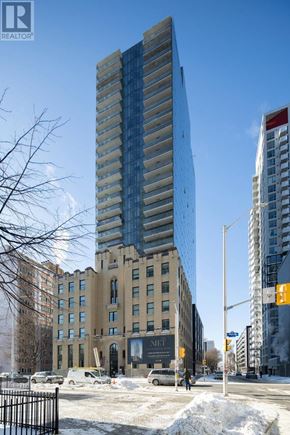 Ottawa apartment for rent - A tall building with a glass facade stands in front of a building with a beige facade.