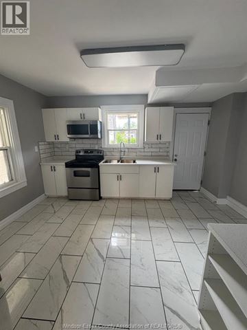 Windsor duplex for rent - A kitchen with white cabinets and a marble floor.