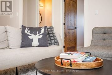 Blue Mountains townhouse for rent - A living room with a couch, a pillow with a deer head, a wooden door, and a coffee table with books and a tray.