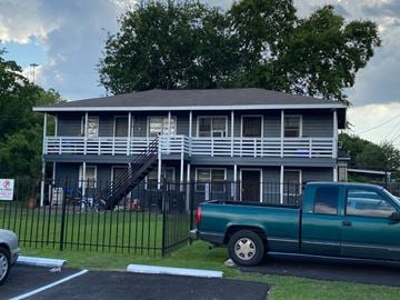 Houston apartment for rent - A green truck is parked in front of a grey house.