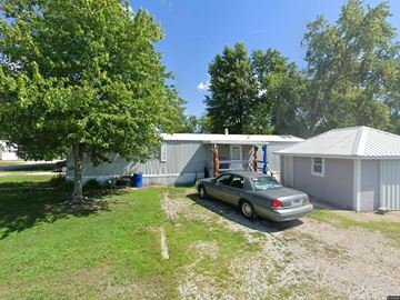 Louisville apartment for rent - A silver car is parked in front of a house with a tree in the background.