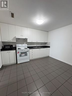 Toronto (South Riverdale) apartment for rent - A kitchen with white cabinets and a black counter top.