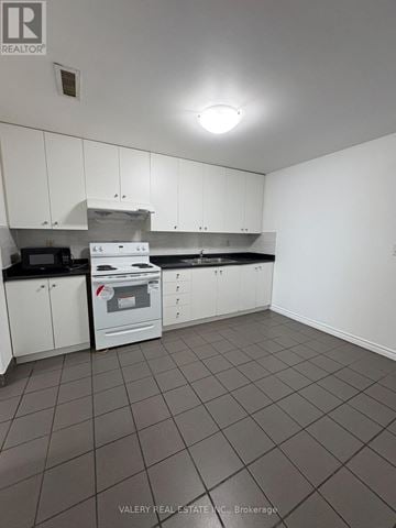 Toronto (South Riverdale) apartment for rent - A kitchen with white cabinets and a black counter top.