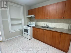 Toronto (University) apartment for rent - A kitchen with white appliances and wooden cabinets.