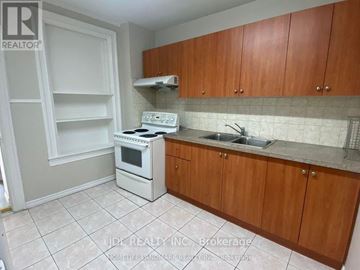 Toronto (University) apartment for rent - A kitchen with white appliances and wooden cabinets.