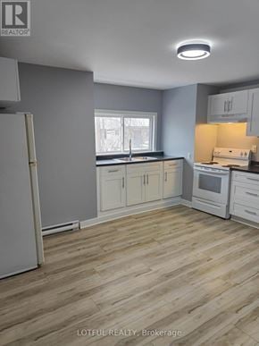 Elizabethtown-Kitley fourplex for rent - A kitchen with wooden floors and white appliances.