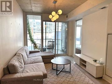 Toronto (South Riverdale) condo for rent - A living room with a grey couch and a round table.