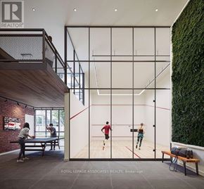 Toronto (Centennial Scarborough) condo for rent - A man and a woman are playing squash in a room with a green wall on the side.