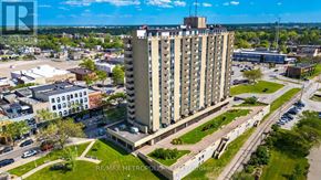 Sarnia condo for rent - A tall building with a parking lot in front of it.