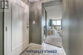 Sarnia condo for rent - A hallway with a door on the left and a living room in the distance.