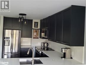 Blue Mountains townhouse for rent - A kitchen with black cabinets and a stainless steel refrigerator.