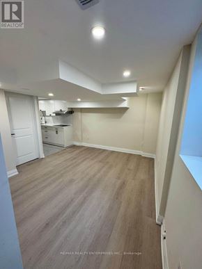 St. Catharines (Carlton/Bunting) apartment for rent - A room with a white door and a kitchen area in the background.