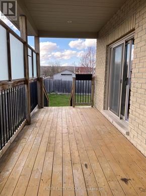 Quinte West (Murray Ward) apartment for rent - A wooden deck with a sliding glass door and a view of a fence and a house in the background.
