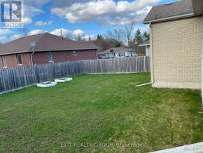 Quinte West (Murray Ward) apartment for rent - A backyard with a wooden fence and a house in the background.