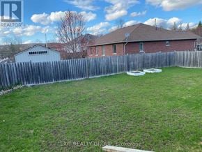 Quinte West (Murray Ward) apartment for rent - A backyard with a wooden fence and a house in the background.