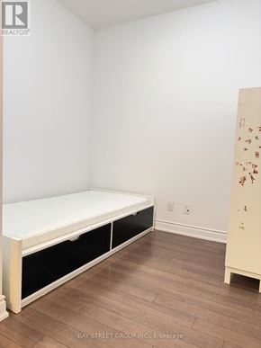 Markham (Unionville) condo for rent - A white bed with black drawers in a room with wooden floors.