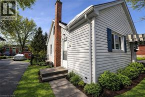 Kitchener apartment for rent - A house with a white siding and a brick chimney is shown.