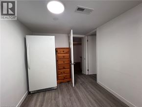 Kitchener apartment for rent - A white refrigerator is in a room with a wooden dresser and a doorway leading to another room.