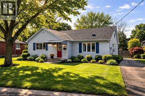 Kitchener apartment for rent - A white house with a red door and a tree in front.