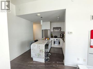 Toronto (Henry Farm) condo for rent - A kitchen area with a table and chairs in the foreground and a refrigerator in the background.