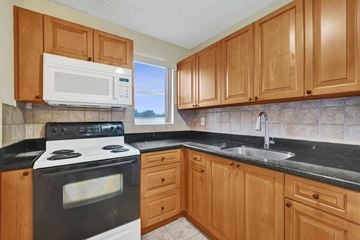 Hallandale Beach apartment for rent - A kitchen with wooden cabinets and a black countertop.