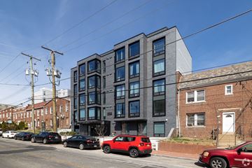 Washington apartment for rent - A modern building with a red car parked in front.