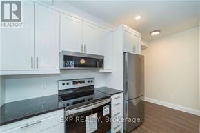 Ottawa apartment for rent - A kitchen with white cabinets and a black stove top oven.