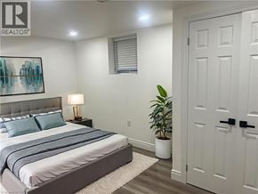 Kitchener apartment for rent - A bedroom with a bed, a lamp, and a plant.