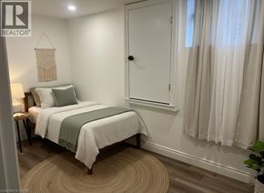 Kitchener apartment for rent - A bedroom with a bed, a nightstand, and a window with curtains.