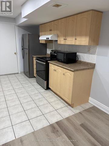 Mississauga (Churchill Meadows) apartment for rent - A kitchen with wooden cabinets and a black microwave.