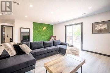 Niagara Falls (Downtown) multi-family for rent - A living room with a grey couch and a green wall.