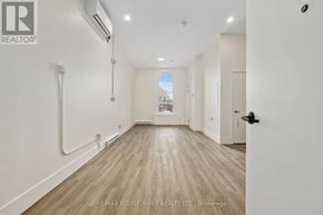 Cobourg apartment for rent - A spacious room with wooden floors and white walls, with a door on the right side.