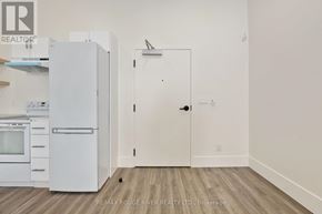 Cobourg apartment for rent - A white refrigerator and oven in a kitchen with a white door.