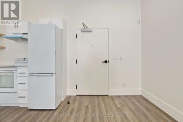 Cobourg apartment for rent - A white refrigerator and oven in a kitchen with a white door.