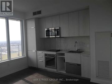 Toronto (Willowdale West) condo for rent - A kitchen with white cabinets and a window overlooking the city.