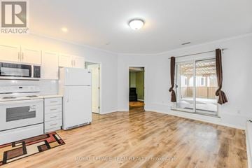 Ottawa apartment for rent - A well-lit, spacious kitchen with white appliances and wooden flooring.