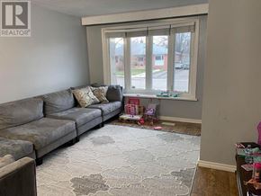 Ajax (South East) apartment for rent - A living room with a grey couch and a rug with a pattern on it.