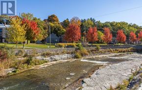 Port Hope apartment for rent - A river flows through a rocky bed with autumn trees in the background.