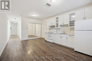 Port Hope apartment for rent - A kitchen with white cabinets and a wooden floor.