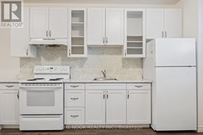 Port Hope apartment for rent - A white kitchen with a refrigerator, stove, and cabinets.