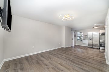 Charlotte apartment for rent - A living room with a television on the wall and a kitchen in the background.